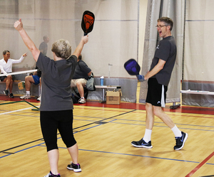 Steve and Karen Pfanenstiel celebrate after scoring a point in pickleball. The couple has been playing the game for a little over a year, primarily practicing at their local YMCA.
