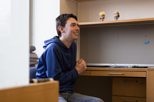 Justin Robbins sits at his office desk. The two “Emperor’s New Groove” figurines on his shelf were a gift from his mother.