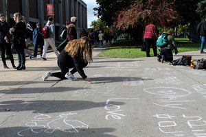 Students write messages in chalk on the pavement of SU’s Quad.